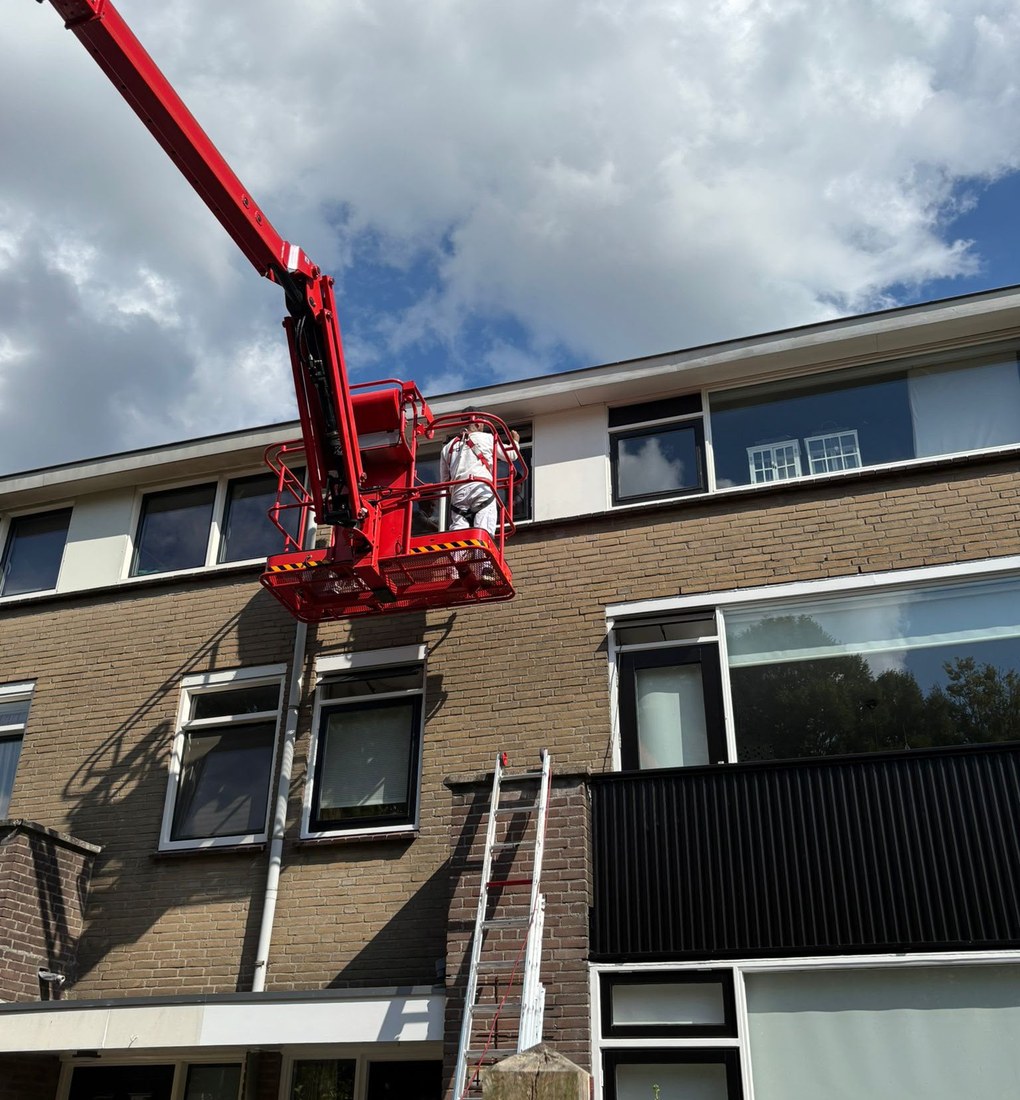 Schilder aan het werk op hoogte vanuit een hoogwerker